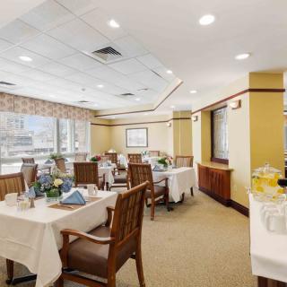 An elegant dining area with neatly arranged tables and chairs, well-lit by large windows.