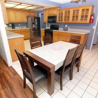 A modern kitchen with wooden cabinets, a dining table set, and various appliances.