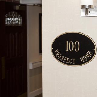 A hallway entrance with a room sign labeled '100 Prospect Home'.