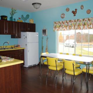 A retro-style kitchen with bright yellow chairs, blue walls, and vintage decorations.