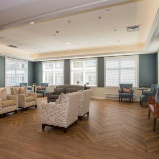 A spacious and well-lit living room with multiple seating options and large windows.