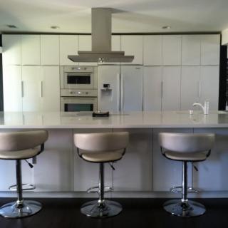 A modern kitchen with a sleek design, featuring a spacious counter and stylish bar stools.