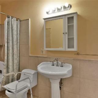 A small bathroom with a pedestal sink, wall-mounted cabinet, and shower curtain.