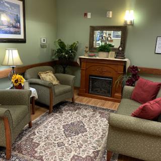 A cozy waiting area featuring comfortable furniture, a warm fireplace, and inviting decor.