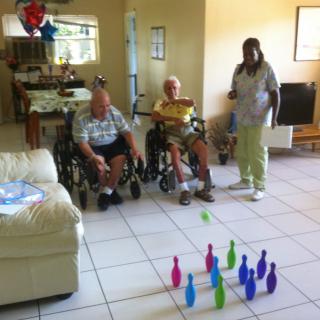 Elderly individuals in wheelchairs participating in an indoor bowling activity.