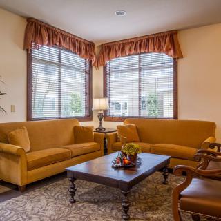 A cozy living room with sofas, a coffee table, and large windows adorned with curtains.