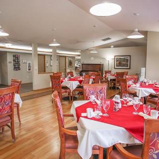 A cozy dining area with red tablecloths and wooden chairs arranged neatly in a well-lit restaurant interior.