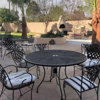 A cozy outdoor patio with a black metal table and chairs, surrounded by a landscaped garden.