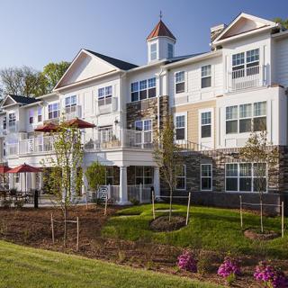 A well-maintained residential building with a landscaped garden and clear blue sky.