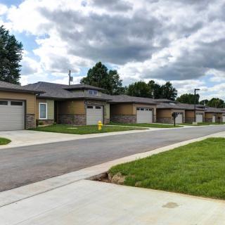 A row of suburban houses with driveways in a quiet residential neighborhood under a cloudy sky.