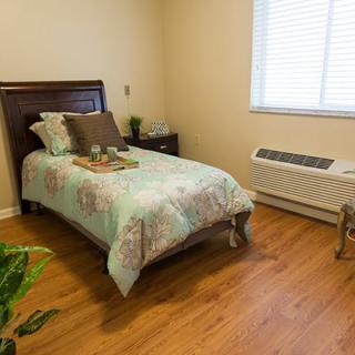 A cozy bedroom with a single bed, wooden flooring, and minimalistic decor.