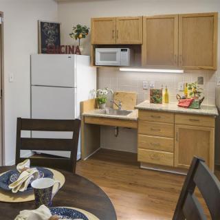 A cozy kitchen and dining area with wooden cabinets, a refrigerator, and a table set for dining.