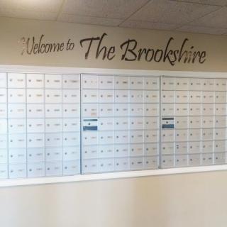 A wall of mailboxes with a 'Welcome to The Brookshire' sign above them.