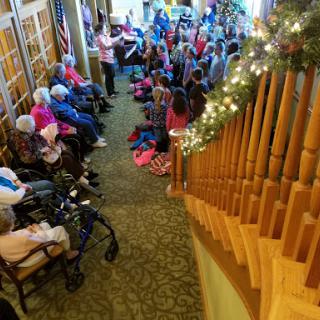 A joyful gathering of seniors and children participating in a performance, surrounded by a festive atmosphere.