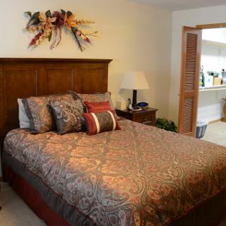 A cozy bedroom featuring a beautifully made bed with decorative pillows and vibrant wall art.