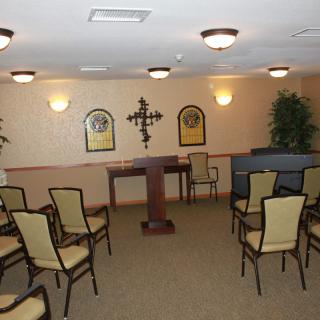 A small chapel or meeting room with arranged chairs, a lectern, and wall decorations.