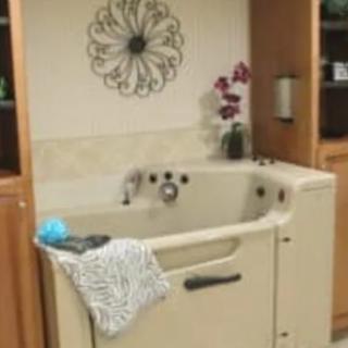 A walk-in tub designed for accessibility, featuring a towel and decorative flowers.
