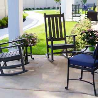 A cozy patio setting with rocking chairs and greenery.