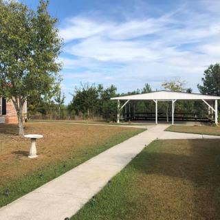 A peaceful garden with a gazebo and a concrete pathway under a blue sky.