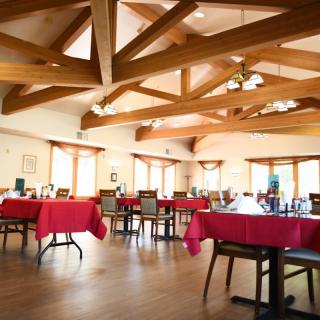A spacious restaurant dining room featuring red tablecloths and wooden beam ceilings.