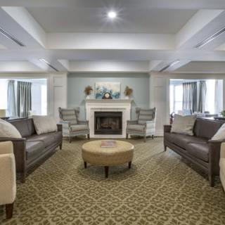 A spacious and elegantly decorated living room featuring a fireplace, sofas, chairs, and a central coffee table.