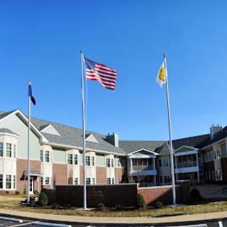 A view of a residential facility with the American flag and a state flag flying in front under a clear blue sky.