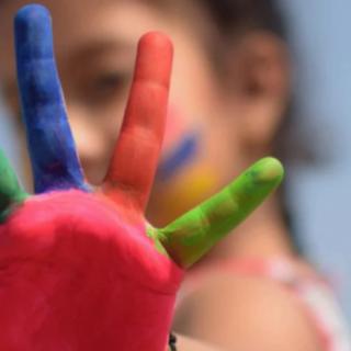 A child with a brightly painted hand showing creativity and fun.