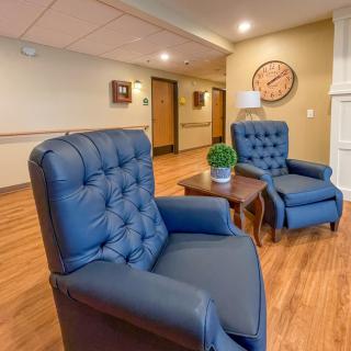 Cozy lounge area with blue armchairs and a wooden floor.