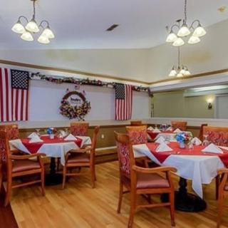 A warmly decorated dining area features tables set with red and white linens, American flags, and a wreath adornment.