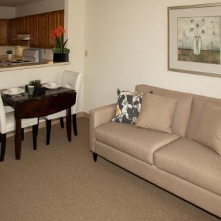 A cozy living room with a beige sofa and dining area in view.