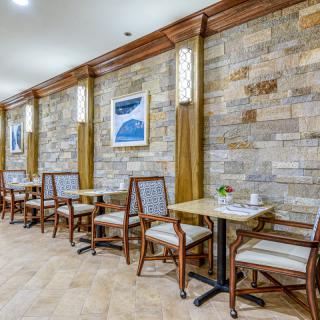 A cozy cafe interior with stone walls, wooden tables, and comfortable chairs.