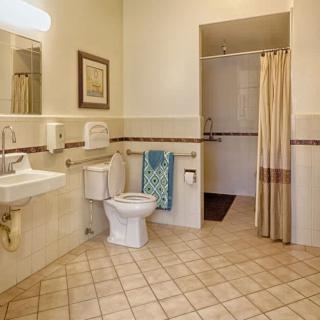 A spacious bathroom with a sink, toilet, and shower area featuring tiled flooring.