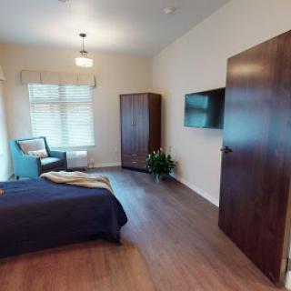 A cozy and modern bedroom featuring a comfortable bed, wooden furniture, and ample natural light.