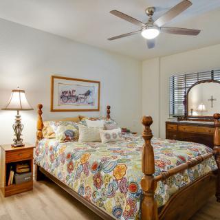 A cozy bedroom with a wooden bed frame, floral bedding, and warm lighting.