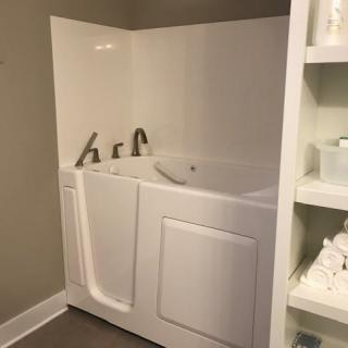 A walk-in tub designed for accessibility and safety in a bathroom setting.
