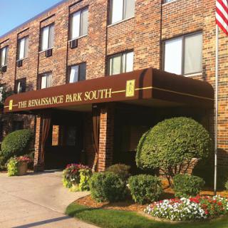 The entrance of the Renaissance Park South hotel, showcasing its brick exterior and well-kept landscaping.