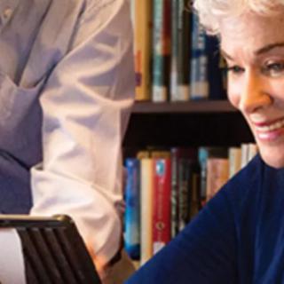 An elderly woman using a tablet in a library setting.
