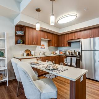 A modern kitchen with wooden cabinets, stainless steel appliances, and a cozy dining area.