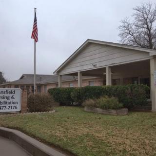 A nursing home building with a flagpole and sign on an overcast day.