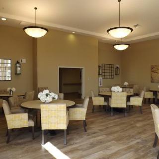 A well-lit dining area featuring several tables and chairs with decorative flowers.