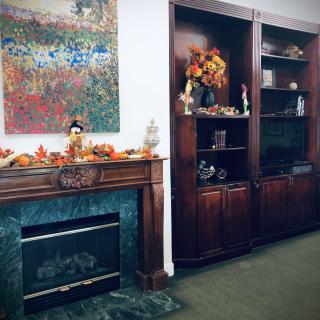 An elegantly decorated room with a fireplace and bookshelves, featuring autumn-themed decor.