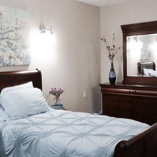 A neatly arranged bedroom with a single bed, dresser, and decorative elements.