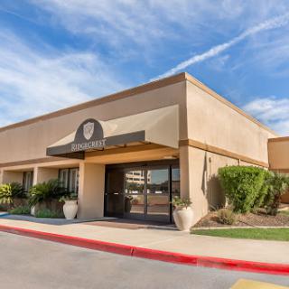 A modern commercial building featuring a welcoming entrance and well-maintained landscaping under a partly cloudy sky.