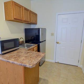A compact kitchen area featuring a microwave, refrigerator, sink, and cabinetry.