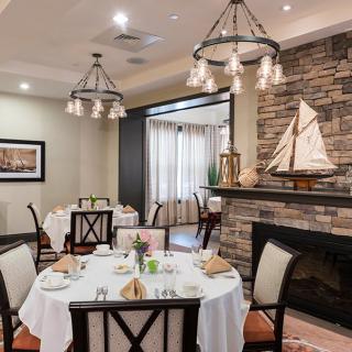 An elegantly set dining room with a stone fireplace and model sailboat decor.