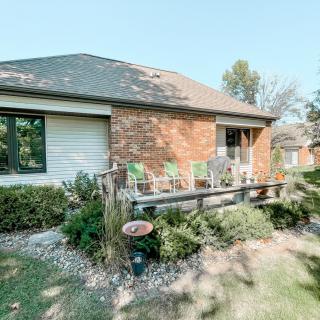 A brick house with a small front yard and patio chairs on a sunny day.