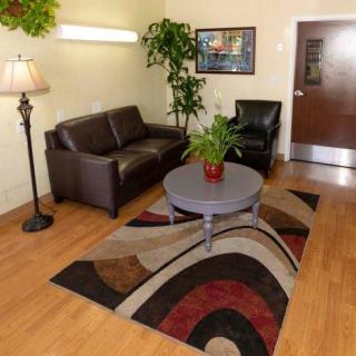 A cozy living room with a brown leather sofa, armchair, and a coffee table on a decorative rug.