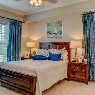A cozy bedroom with stylish decor and a comfortable bed, featuring blue curtains and matching pillows.