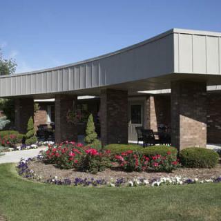 A modern building surrounded by a landscaped garden with vibrant flowers and greenery.