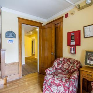 A cozy interior with wooden doors, a floral armchair, and wall decorations beside a hallway.